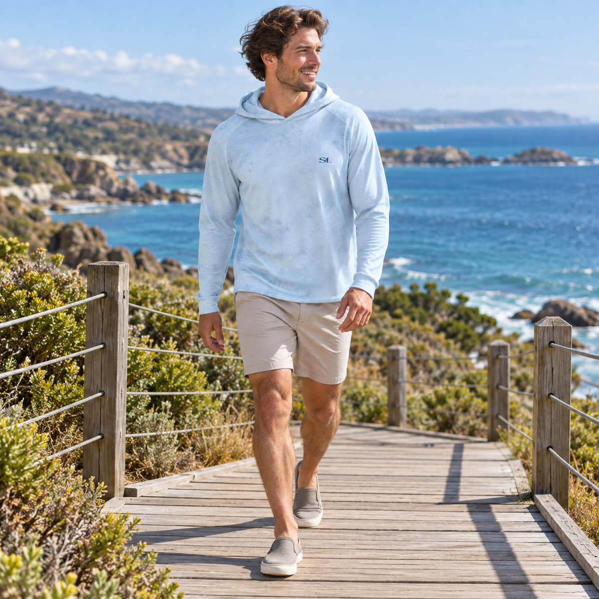Man wearing Low Tide Sky Sun Hoodie, wider coastal view